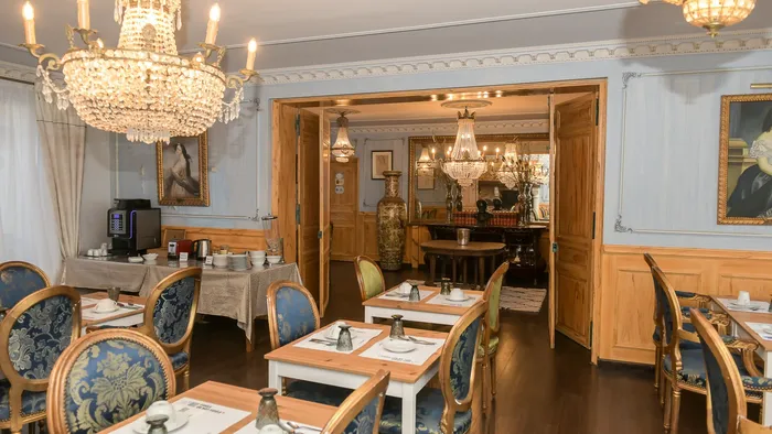 Élégant salon de petit-déjeuner avec tables et chaises, lustres, et portes ouvertes au Hôtel Villa Aultia.