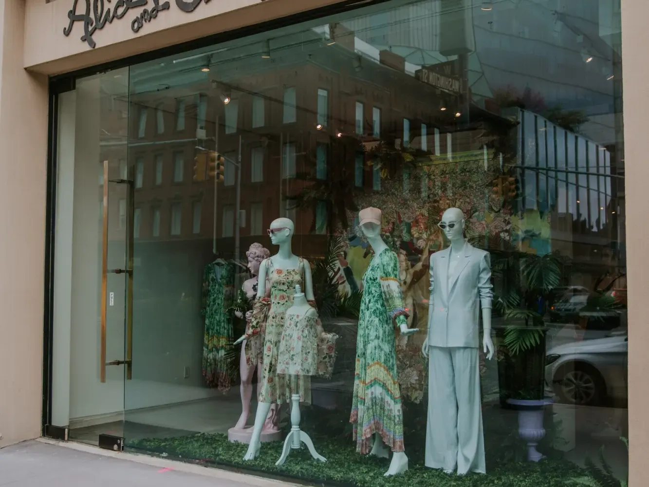 Fashion store with glass facade showcasing mannequins in floral and white suits, under 
