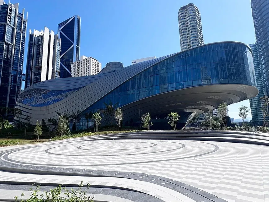 Prominent circular structure of Ombak KLCC next to a park.