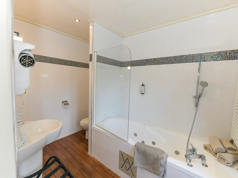 Salle de bain avec baignoire spa et sèche-cheveux à l'Hôtel Villa Aultia à Ault.