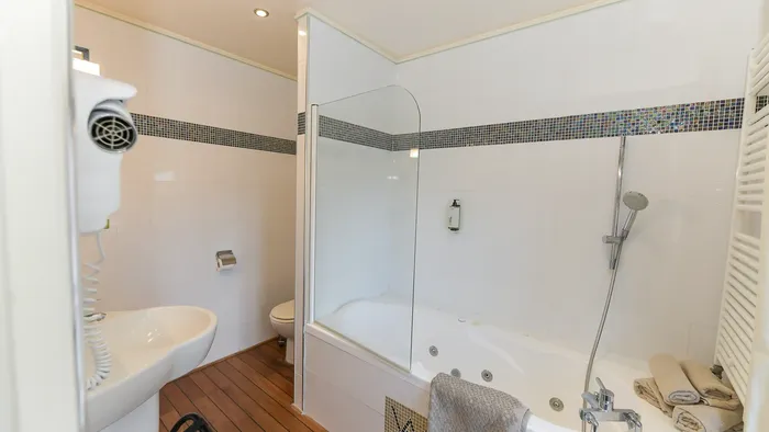 Salle de bain avec baignoire jacuzzi et toilettes à l'Hôtel Villa Aultia.