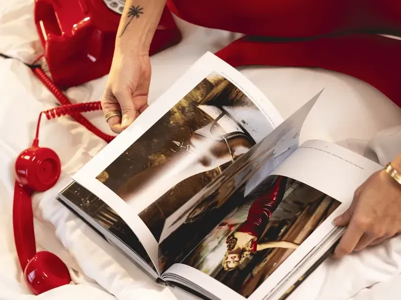 Close-up of a magazine and vintage red rotary telephone on white hotel bedding at Urban Hive Madrid
