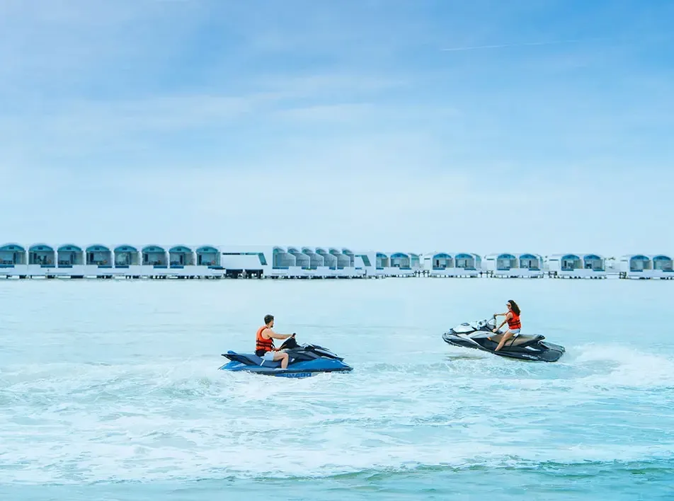 A couple riding jet skis with a scenic beach resort in the background - Lexis MY