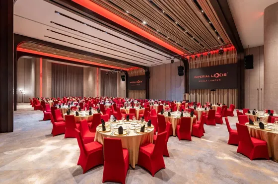 Sophisticated luxury event venue with red mood lighting and large LED screens for corporate annual dinners.