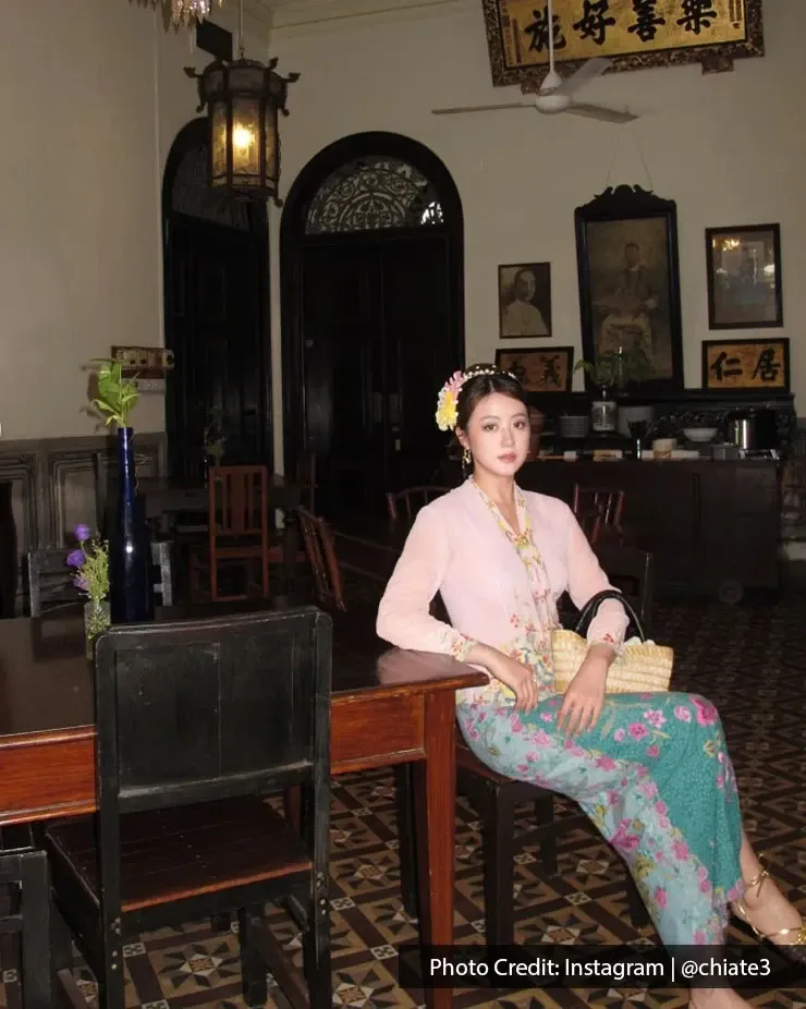 Woman in traditional Peranakan attire sitting inside Cheong Fatt Tze Blue Mansion.