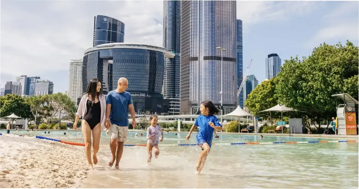 A family strolling along the sand at Streets Beach in South Bank, Brisbane
