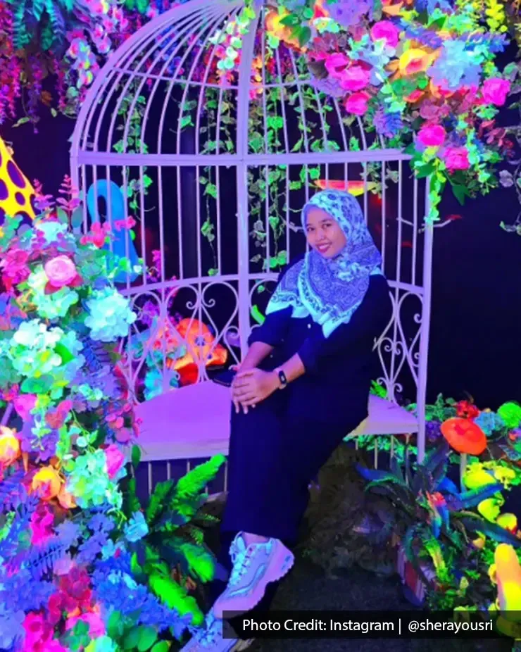 Visitor sitting inside a glowing floral setup at Glow Planet Penang