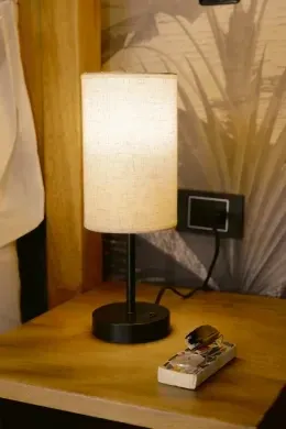 Bedside lamp and remote control on a wooden table beside the bed at Unika Hotels, fine for the best area to stay in Bogota