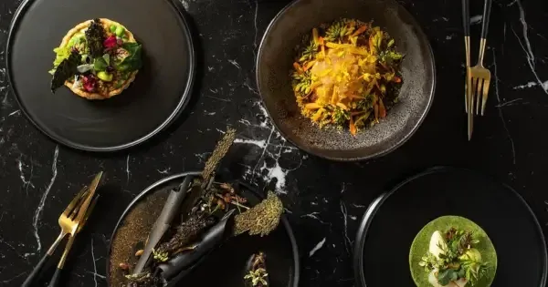 Gourmet dishes and red wine elegantly plated on black marble table with gold cutlery