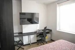 Guest room with wall-mounted TV and desk by a bright window at Unika Hotels, the best places to stay in Bogota