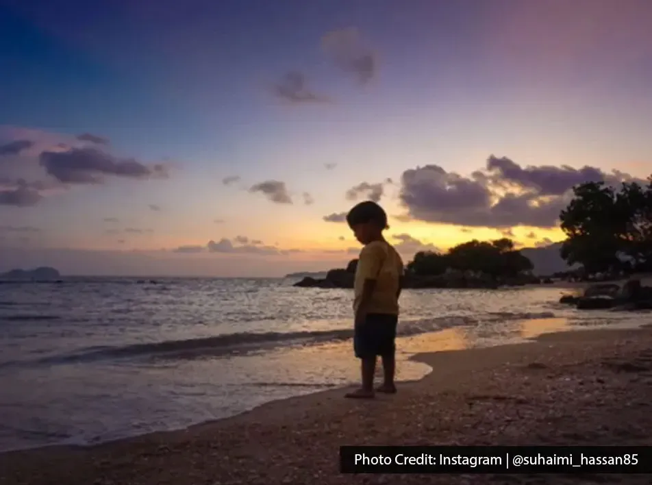 Scenic sunset view with a boy at the beach in Pantai Teluk Bayu