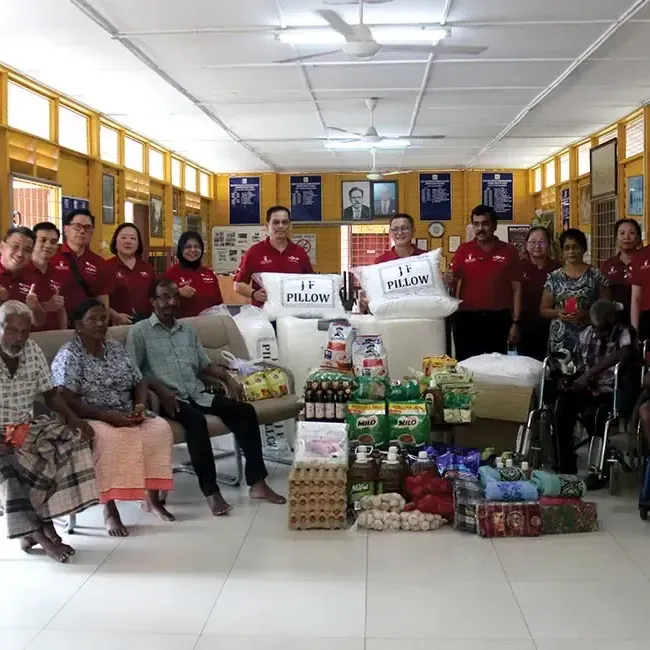 A group of people surrounded by essential donations and posing for the photo - Lexis Port Dickson