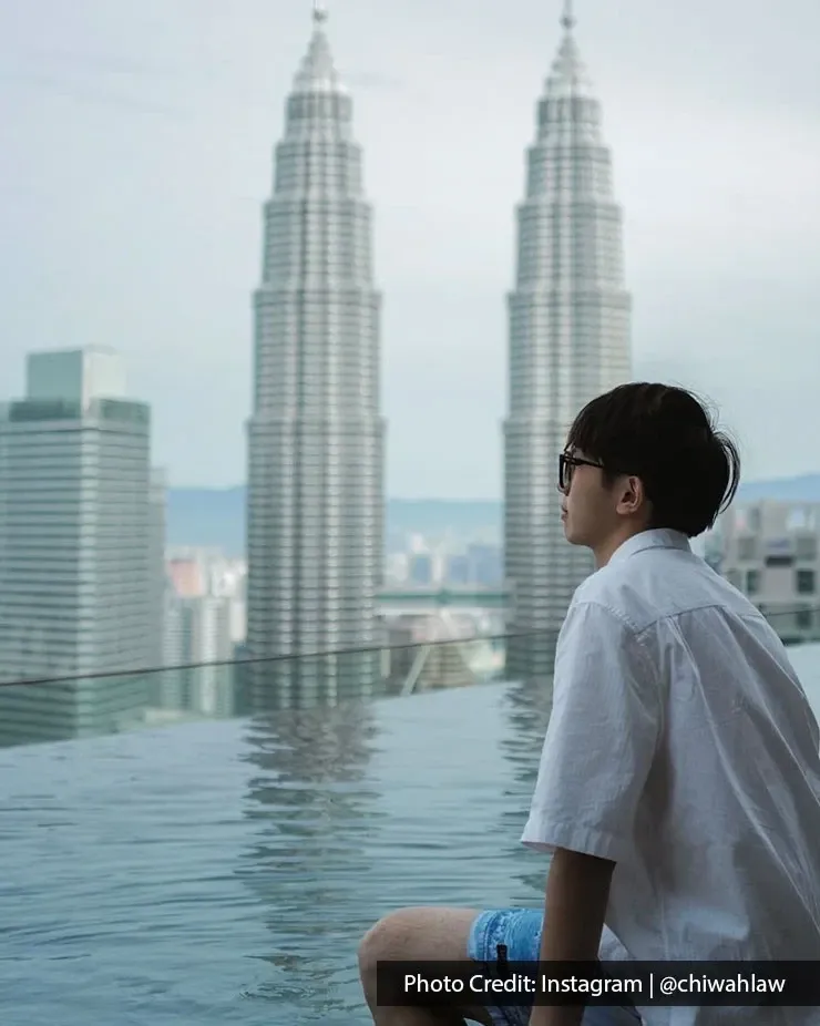 Visitor beside rooftop pool with Petronas Twin Towers view.