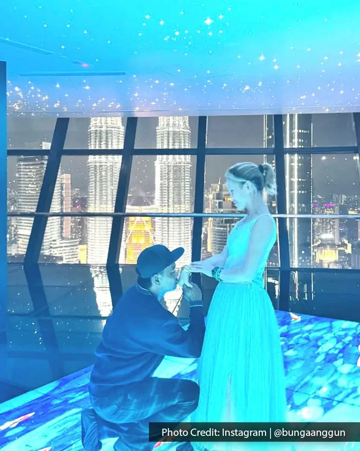 A couple stands on a platform with a panoramic KLCC view, sharing a special romantic moment together.