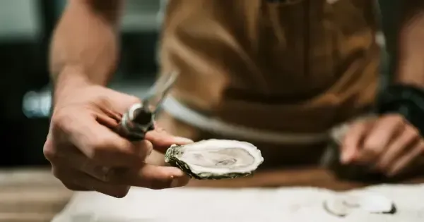Man serves a freshly shucked oyster to guests in a Hobart restaurant