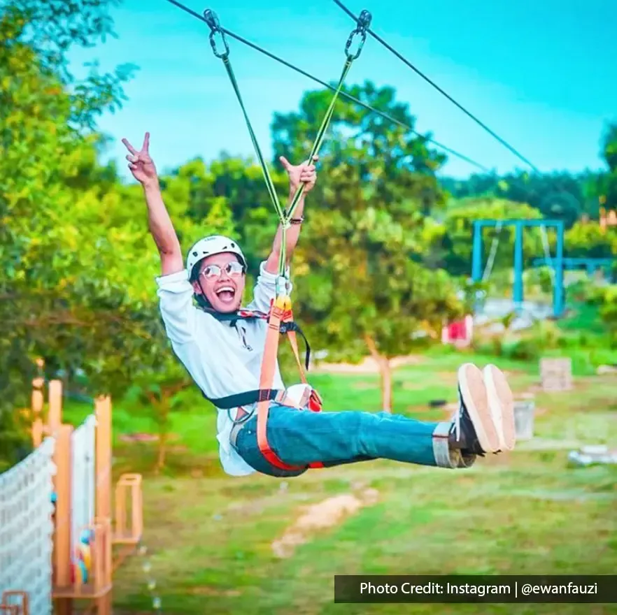 girl doing flying fox activity happily with green scenery