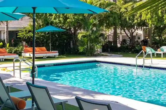 Pool courtyard at The Vagabond Hotel Miami with turquoise umbrellas, lounge chairs, and tropical landscaping