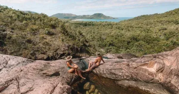 Two people sitting atop Zoe Falls on Hinchinbrook Island, Townsville