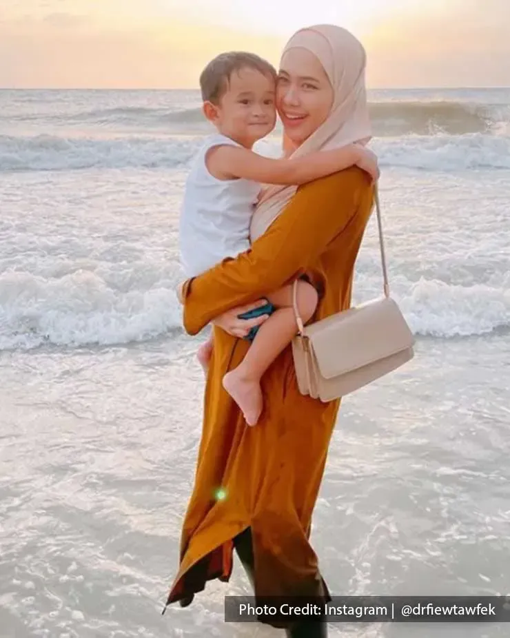 Woman carrying a baby on a beach in Port Dickson - Lexis Hibiscus