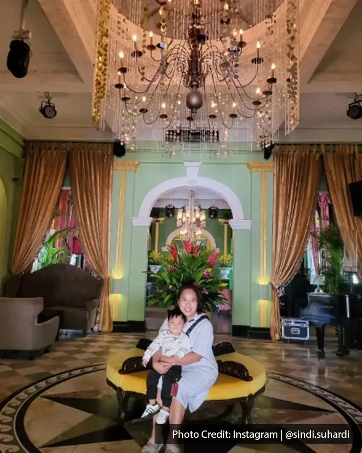 Woman with child seated under a chandelier inside Beach Blanket Babylon.