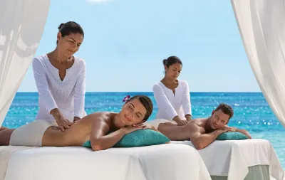 Couple profitant d'un massage relaxant sur la plage du Secrets Resort Spa à Saint Martin Beach Resort & Spa