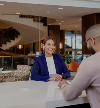 Smiling hotel employee assisting a guest at the welcoming front desk of The Whitehall Houston
