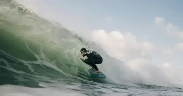 Surfer in full body wetsuit rides a wave at Lyall Bay beach in Wellington 