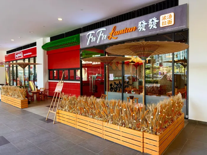 Exterior of Fu Fu Lamian restaurant with large wooden planters of dried grass and two umbrellas at Sunway Velocity Hotel