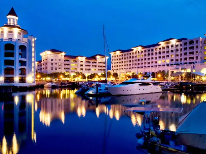 Night view of Straits Quay Marina with boats docked and the mall illuminated in the background - Lexis Suites Penang