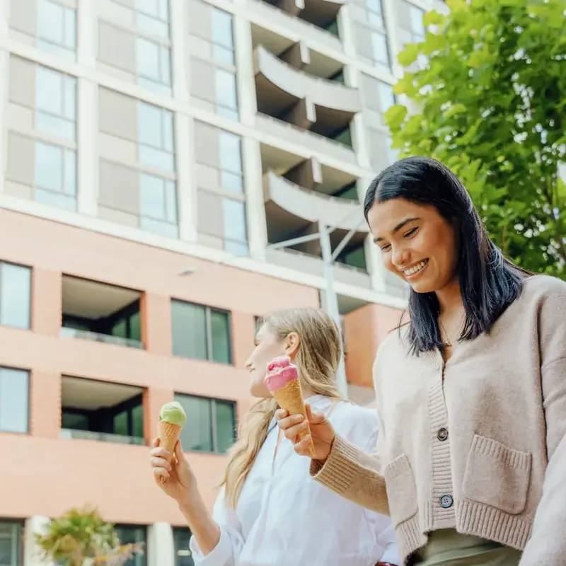 Two women holding ice creams in front of Caulfield Place building.