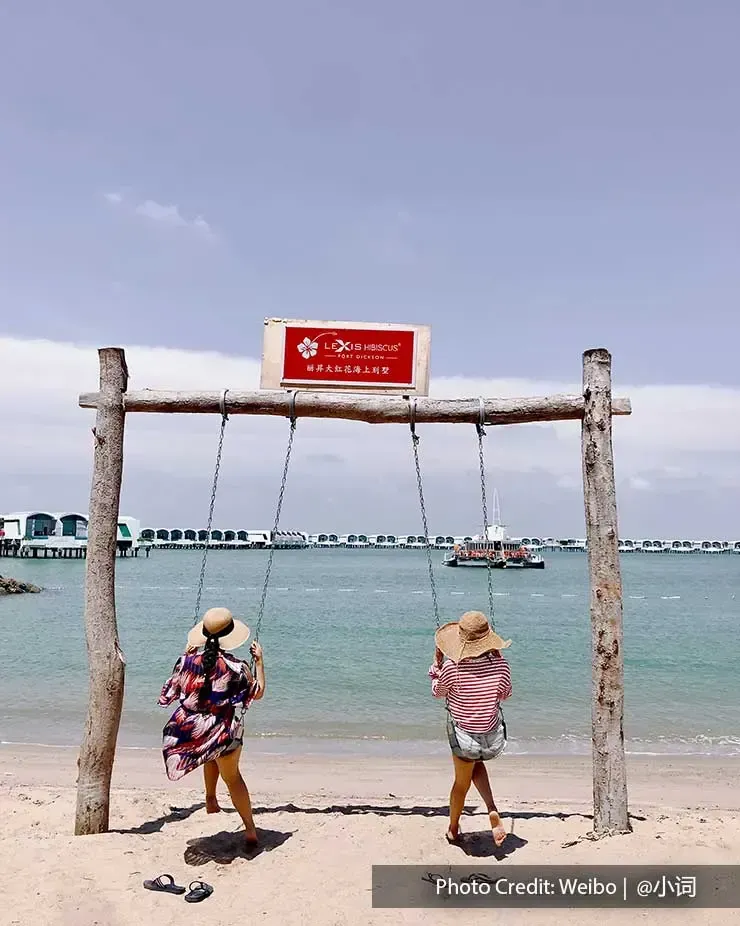 Two womens sitting on a swing at the beach in Lexis Hibiscus