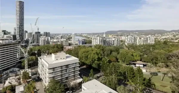 Cityscape view of Brisbane with green park under a clear blue sky.