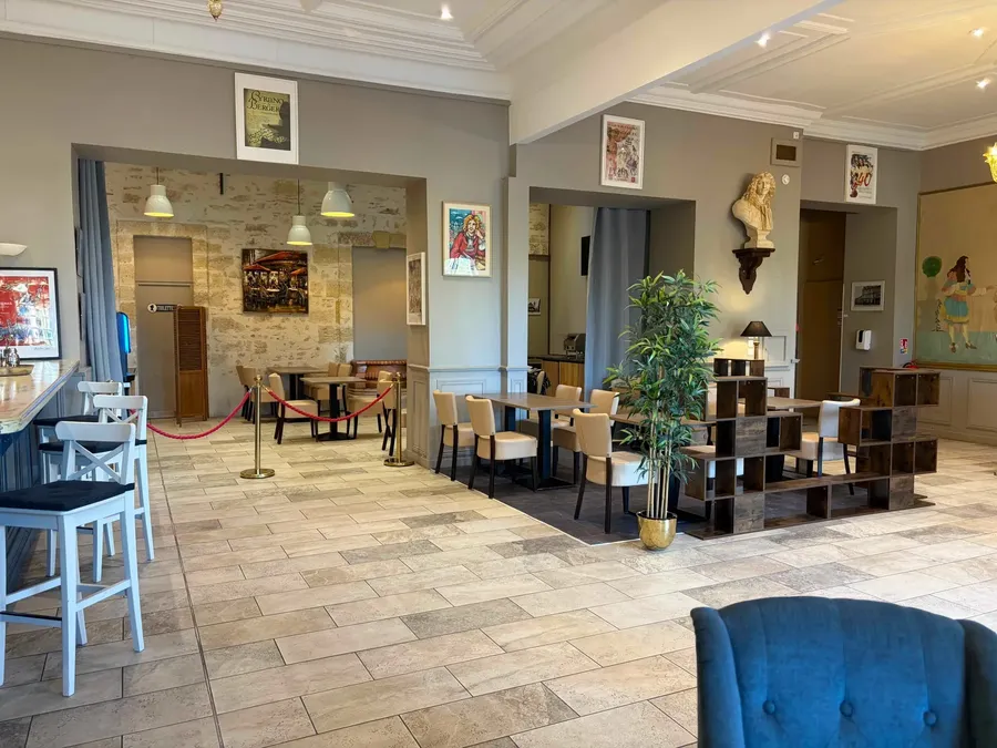 Salon avec tables, chaises, bar et objets décoratifs au Grand Hôtel Molière.