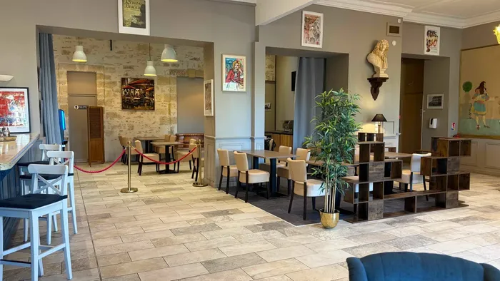 Salon avec tables, chaises, bar et objets décoratifs au Grand Hôtel Molière.