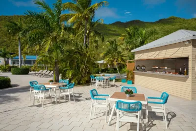 Dîner en plein air au Saint Martin Beach Resort & Spa, qui dispose d'un bar extérieur avec de petites tables et des chaises bleu vif.