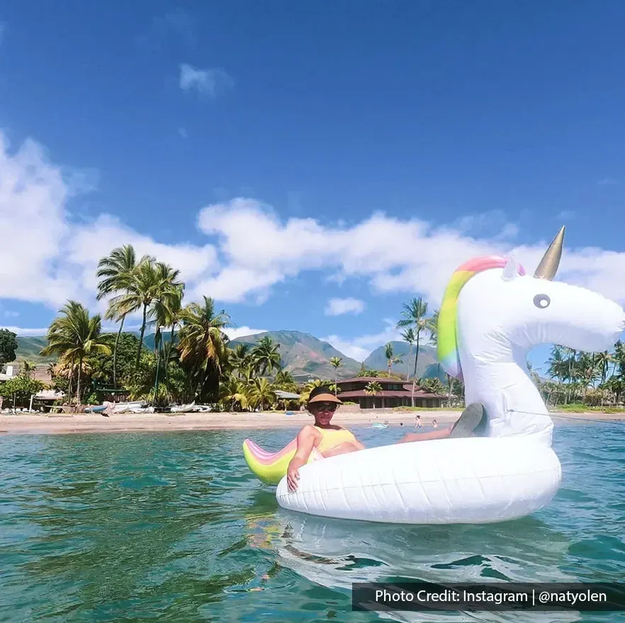 A woman relaxing on a unicorn float during her beach vacation - Lexis MY