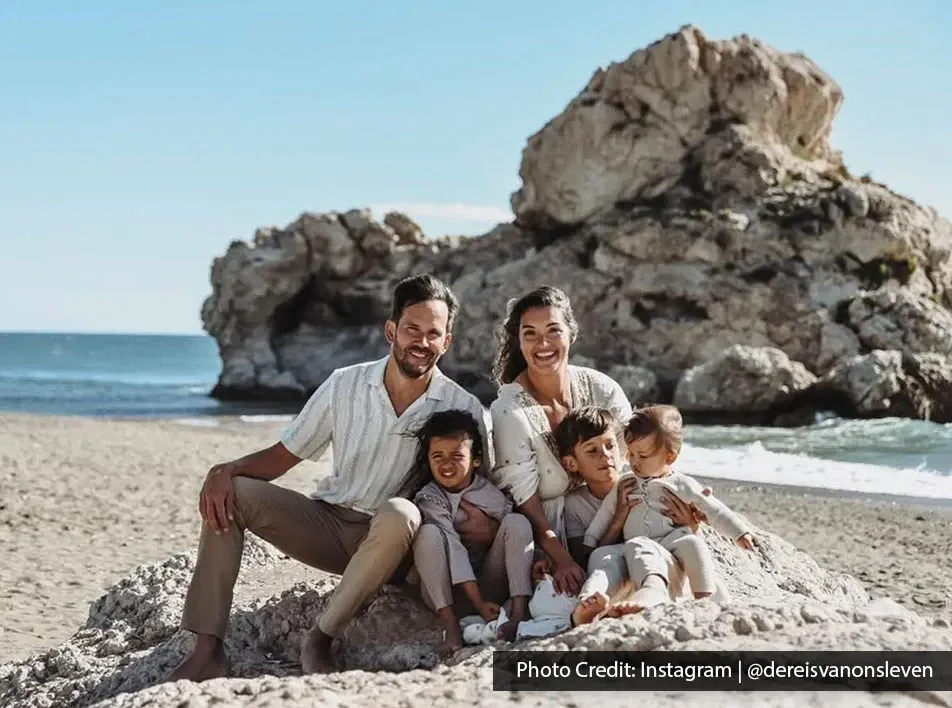 Family sitting together on rocky beach by sea.