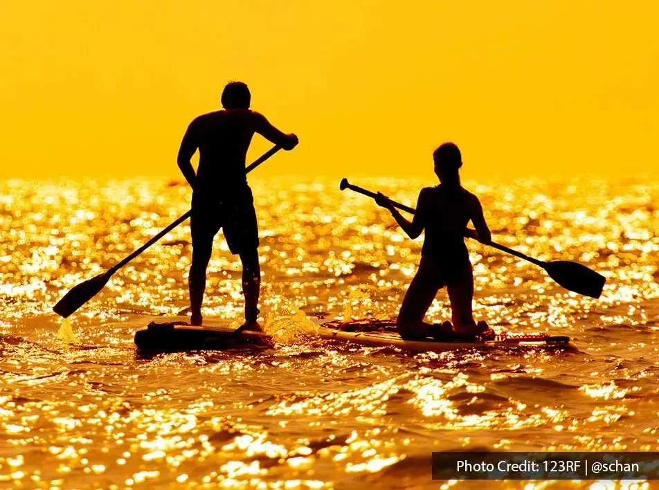 young couple paddleboarding in the ocean - Grand Lexis PD