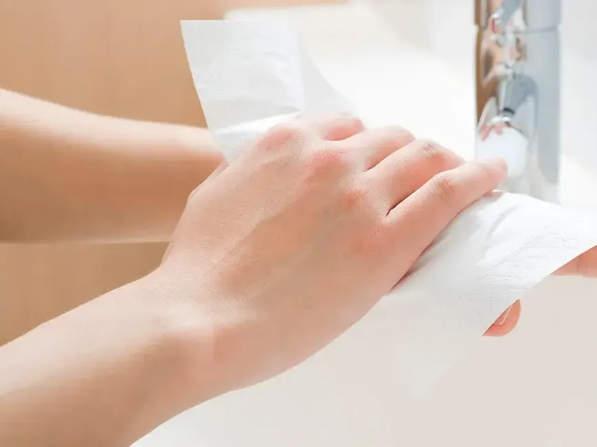 A person drying their hands with a paper towel - Lexis Hotels & Resorts