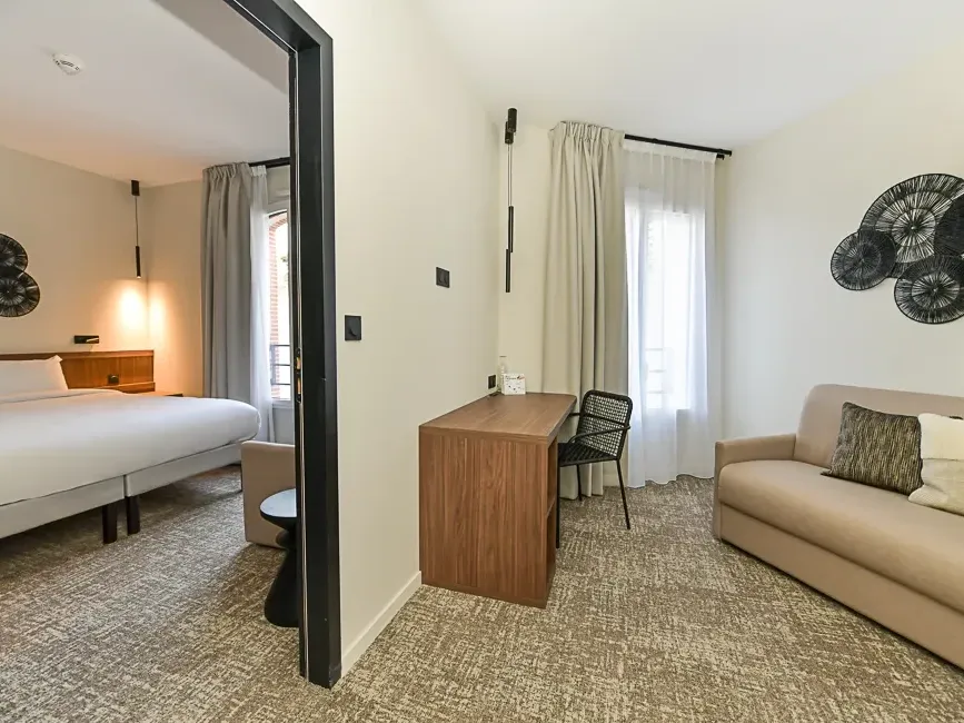 Suite familiale élégante avec lit double, canapé et bureau à Hôtel Rivella à Clisson.