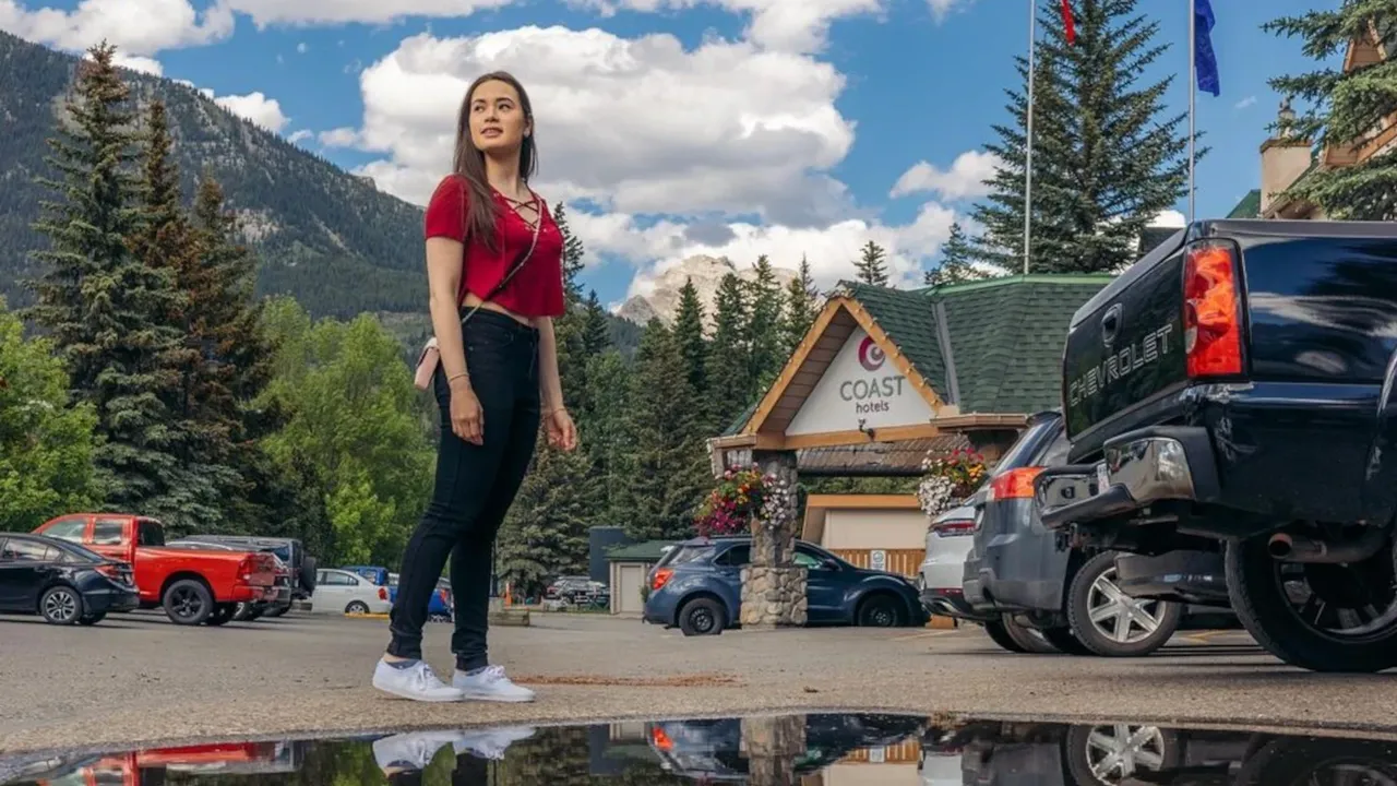 A person poses out their hotel before heading on a walk to explore Canmore on foot.