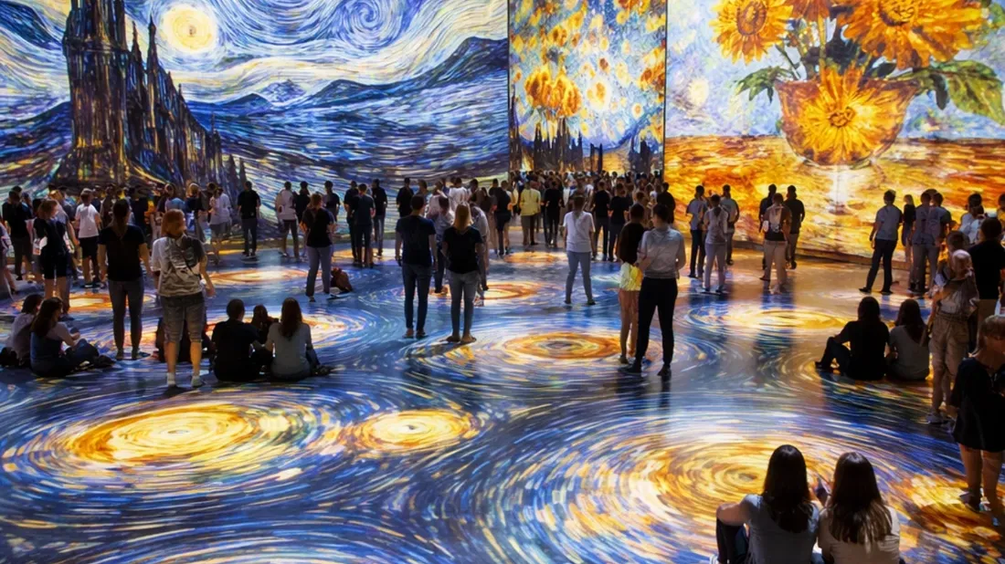 Large crowd gathered around immersive art exhibit with swirling Van Gogh paintings on walls.