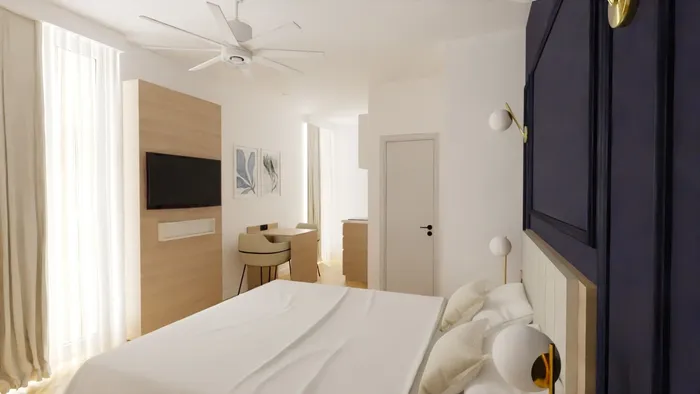 Chambre moderne avec lit, bureau, télévision et ventilateur de plafond chez Les Sources Callou.