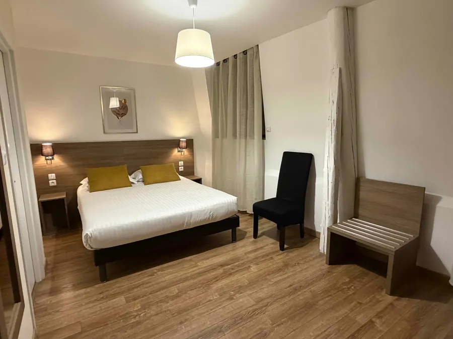 Chambre classique avec lit double et chaise au Grand Hôtel Molière à Pézenas.