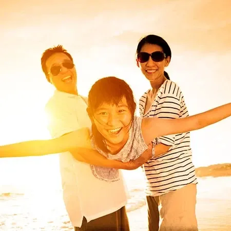 Family enjoying Port Dickson beach during golden sunset.