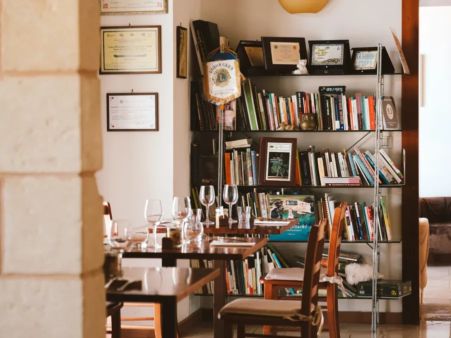 Bibliothèque pleine de livres et de verres à vin à côté d'une table à Masseria Stali.
