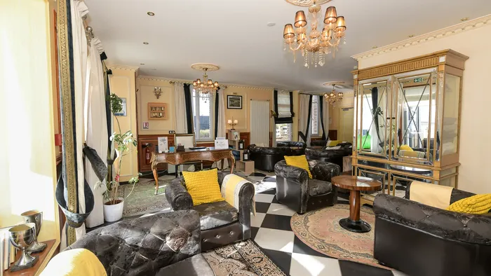 Salon élégant avec meubles noirs et coussins jaunes à l'Hôtel Villa Aultia.