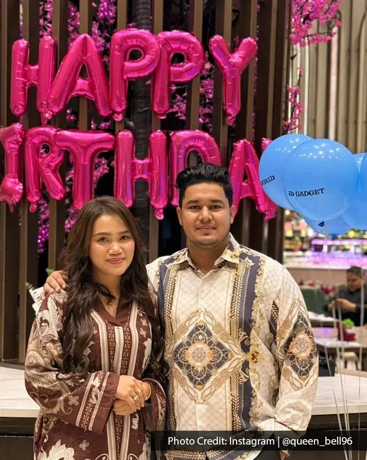 A couple taking a birthday photo together with a happy birthday decor in the background.