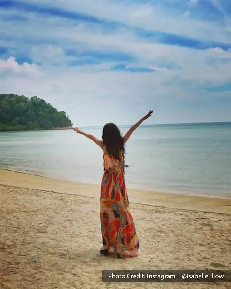 Woman holding hands out on a beach in Lexis Hibiscus