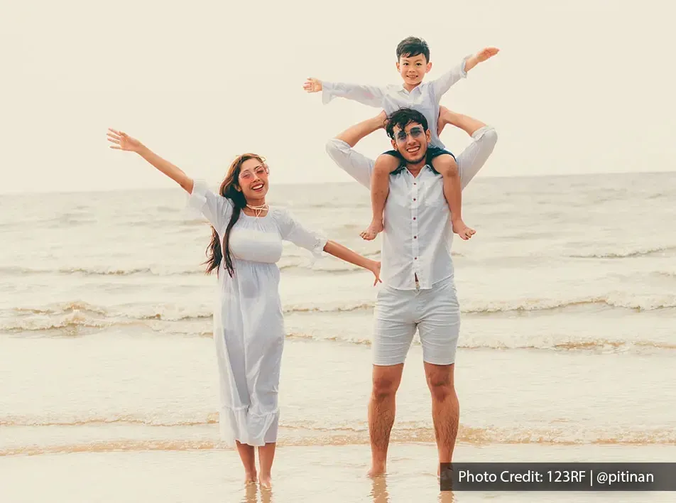 A family dressed in matching outfits enjoying their vacation time on a beach - Lexis MY